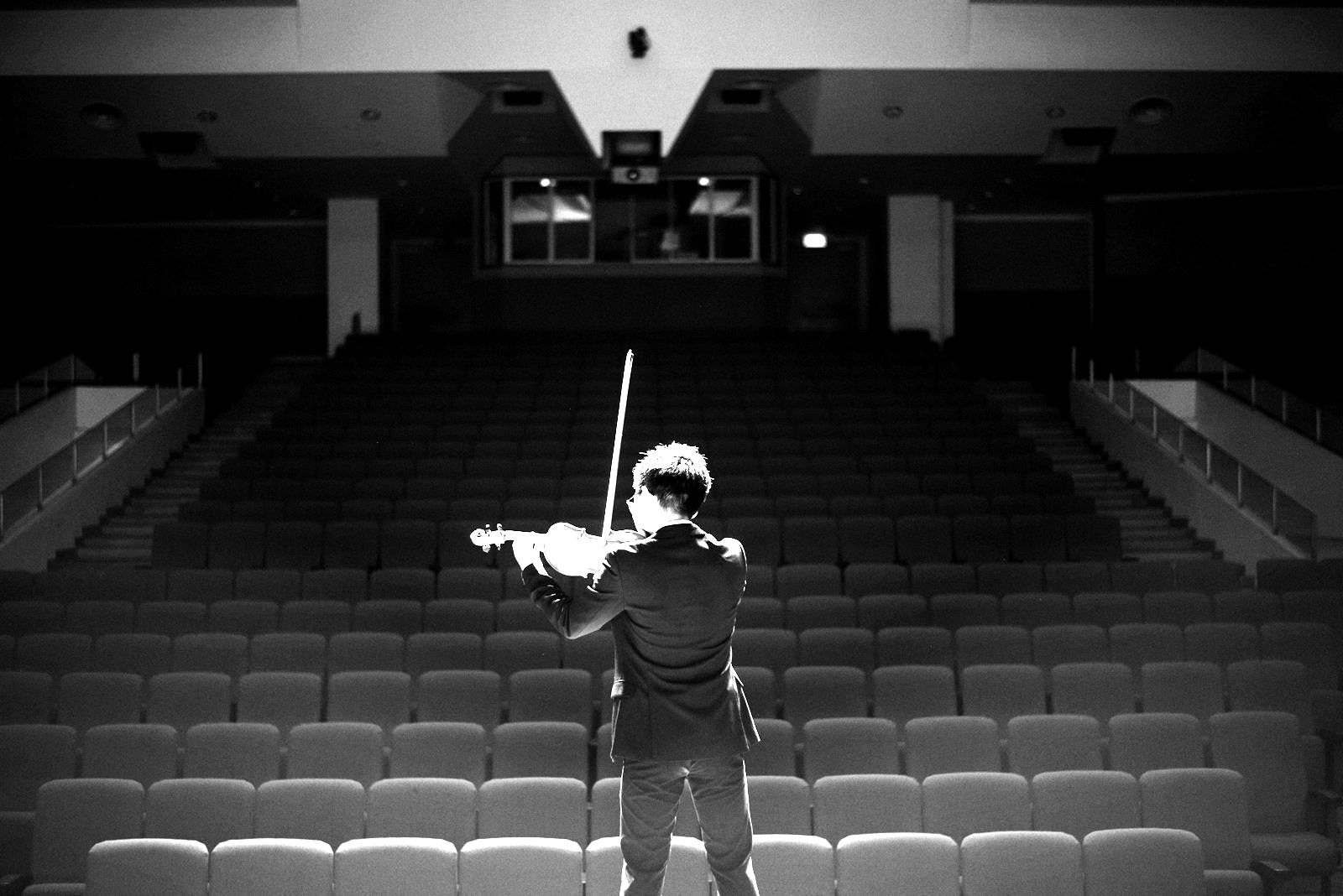 A violinist rehearsing to an empty concert hall