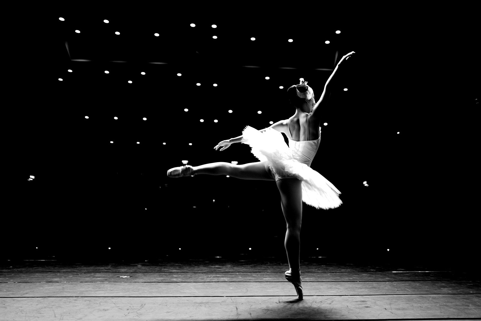 A ballerina mid-performance on a dark stage